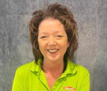 Woman standing in front of gray backdrop with lime green shirt on