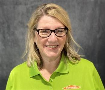 Female with glasses, wearing a lime green SERVPRO shirt, standing in front of grey backdrop