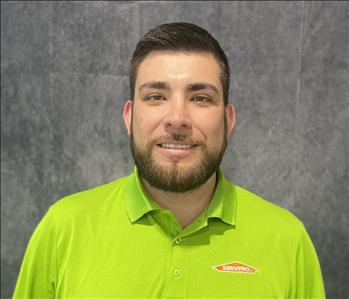 Male employee wearing lime green shirt standing in front of grey backdrop