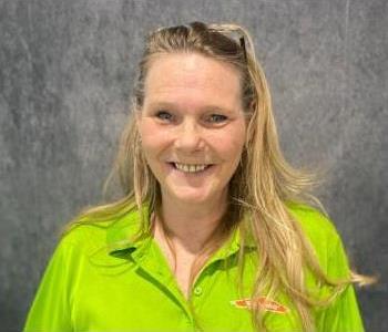 Woman standing in front of gray backdrop with lime green shirt on