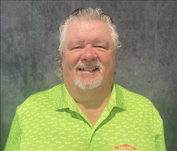 Male standing in front of gray backdrop with lime green shirt on